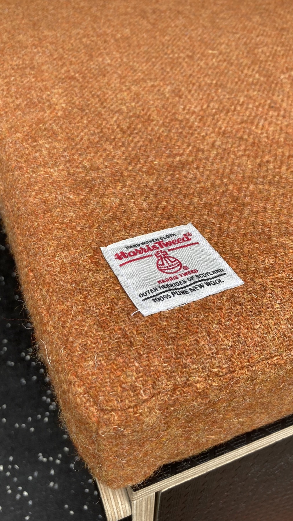 Close-up of Harris Tweed orb label on rust-orange cushion